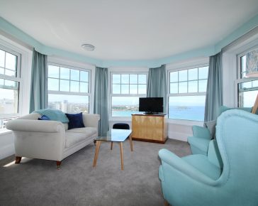 Round hotel room with windows overlooking the sea.