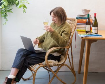 Woman sat in a chair tasting wine on a video course